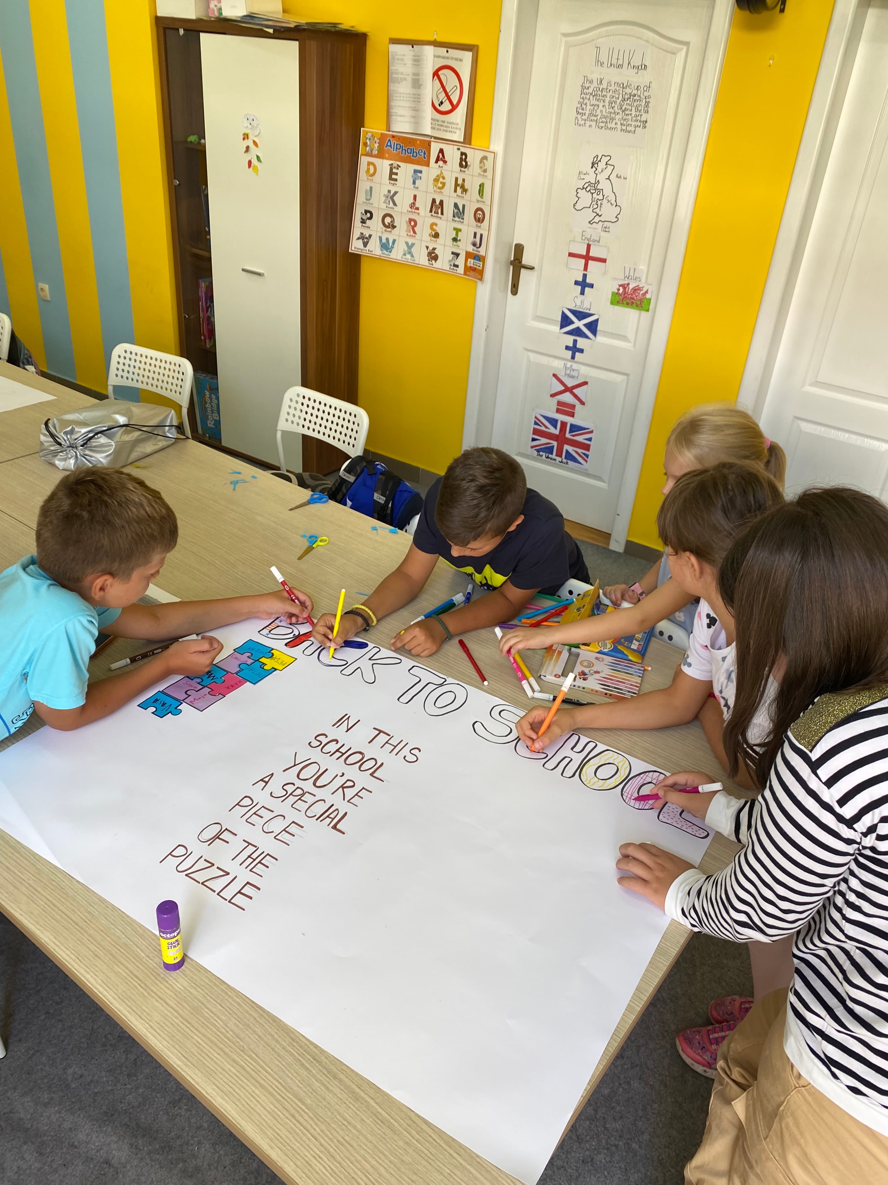 Deca zajedno rade na velikom posteru „Back to School – In this school you're a special piece of the puzzle“.